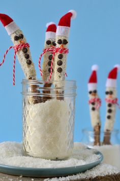 snowmen made out of marshmallows in a jar with santa hats on top