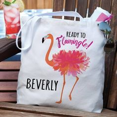 a white tote bag sitting on top of a wooden bench next to a drink