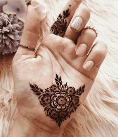 two hands with henna tattoos on their palms and one hand holding an open flower