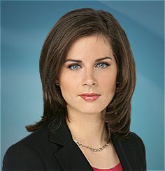 a woman with brown hair and blue eyes is posing for a photo in front of a white background