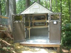 an outhouse in the woods with its doors open