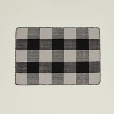 a black and white checkered placemat on a gray surface with an embroidered edge