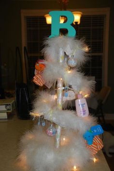 a white christmas tree decorated with feathers and lights in the shape of letter b, on top of a table