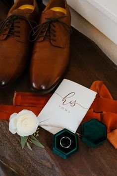 a pair of brown shoes sitting on top of a wooden floor next to an orange ribbon