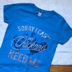 This Tee Shirt Had Me At “My Chickens Need Me”. For All The Chicken Parents Out There, Both Farm And Suburbs Alike, This One’s For You. In Nwot Euc Like New Condition, A Teal Or Turquoise Blue Tee Shirt (My Camera Makes The Color Appear Darker Than It Actually Is) In A Size Small. 100% Cotton. The Font Is Silver And The Very Detailed Illustrations Of Chickens In Back Are A Black Or Very Dark Blue Color. You Can See Feathers And The Eyes On The Faces Of The Chickens. This Gildan Tee Is A Heavy Co Silver Graphic Print Cotton Top, Silver Cotton Top With Graphic Print, Silver Cotton Tops With Graphic Print, Blue Tee, Dark Blue Color, The Chicken, Turquoise Blue, Teal Blue, Blue And Silver