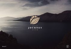 a logo for a travel company called journey club on the side of a mountain with water and mountains in the background