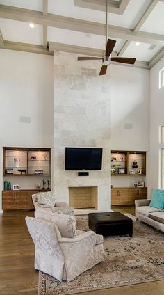 a living room with couches, chairs and a television on the wall in front of a fireplace