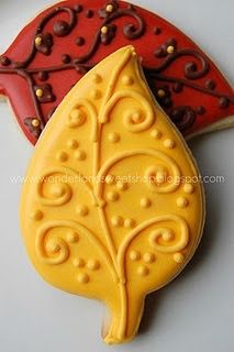 two decorated cookies sitting next to each other on a white plate with red and yellow decorations