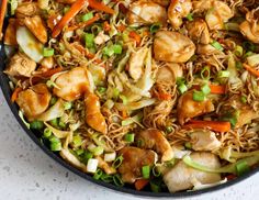 a skillet filled with noodles, chicken and veggies on top of a table