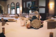 an old fashioned lantern sits on top of a white table cloth covered table with place settings