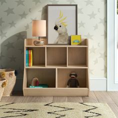 a book shelf with books and toys on it next to a wallpapered room