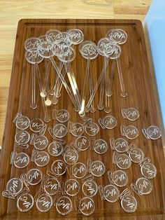 a wooden cutting board topped with lots of glassware and spoons on top of it