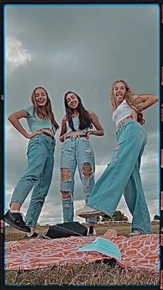 three young women standing on top of a blanket