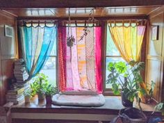 the window is decorated with colorful curtains and potted plants