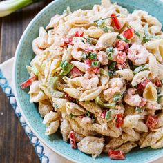 a bowl filled with pasta salad on top of a wooden table