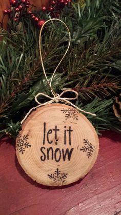 a wooden ornament that says let it snow hanging on a christmas tree branch