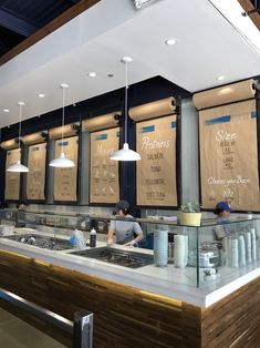 the interior of a restaurant with menus hanging on the wall and people working behind the counter