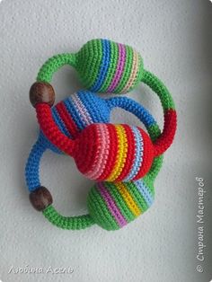 two crocheted rings with wooden beads on them sitting next to each other in front of a white wall