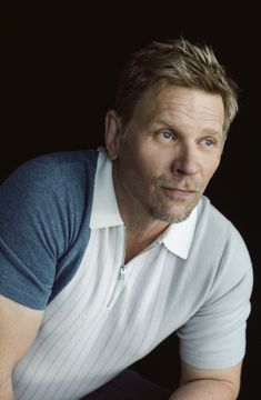 a man in a polo shirt is posing for a photo with his hands on his knees