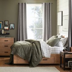 a bed sitting under a window in a bedroom next to a wooden dresser and chair