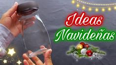 a person holding a wine glass in their hand with christmas decorations and lights on the background