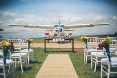 an airplane sitting on top of a grass covered field next to white chairs and flowers