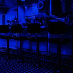 a row of bar stools sitting in front of a kitchen counter with blue lights