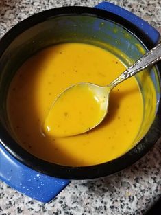 a spoon in a bowl filled with yellow liquid