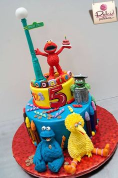 a birthday cake with sesame street characters on top and the number five in the middle