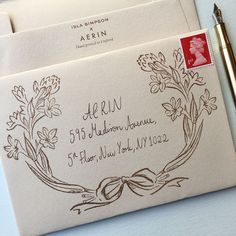 two envelopes with writing on them next to a pen and inking stamper