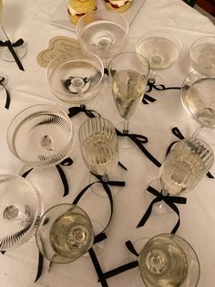 a table topped with wine glasses and plates filled with desserts on top of a white table cloth