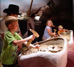 two children are playing with an old fashioned sink in a museum setting while others look on