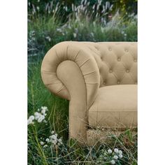 a couch sitting in the middle of some tall grass and flowers on it's side