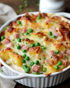 a casserole dish with peas, ham and cheese in it on a table