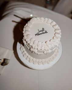 two tiered cake sitting on top of a white table with silverware next to it