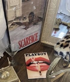 a magazine sitting on top of a wooden floor next to a glass vase and mirror