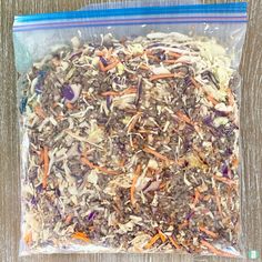 a plastic bag filled with shredded carrots and other vegetables on top of a wooden table