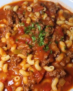 a white bowl filled with pasta and meat in tomato sauce, garnished with parsley