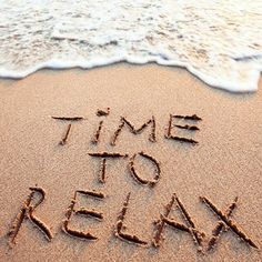 the words time to relax written in sand at the beach