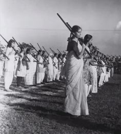 an old black and white photo of women in sari marching with their instruments on the field