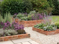 an outdoor garden area with brick walls and plants in the center, surrounded by gravel