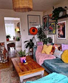 a living room filled with furniture and lots of plants on top of the tables in front of them