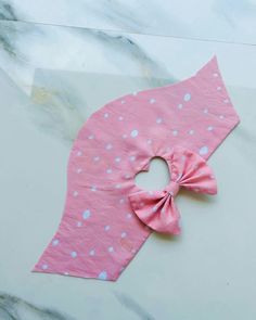 a pink and blue polka dot bow tie on top of a marble counter with white speckles