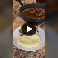 a white plate topped with mashed potatoes next to a skillet filled with meat