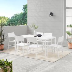 a white table and chairs sitting on top of a rug next to potted plants