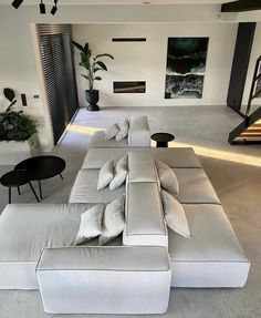 a modern living room with white couches and black tables