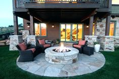 a fire pit sitting in the middle of a lush green field next to a building