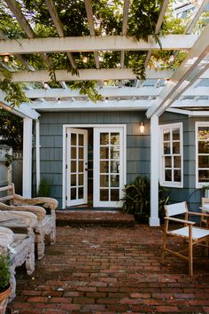 an outdoor patio with chairs and tables under a pergolated roof over brick pavers