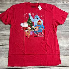 a red t - shirt with the characters from rudolph and santa clause in front of a christmas tree