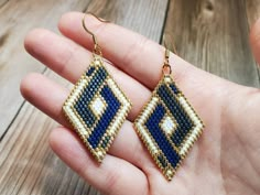 a hand holding a pair of blue and white beaded earrings